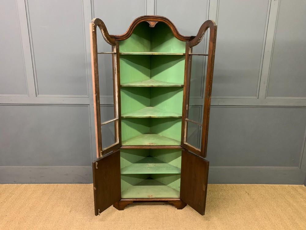 A tall burr walnut corner cabinet featuring an arched double-domed glazed upper section over a lower cupboard with panelled doors. View V