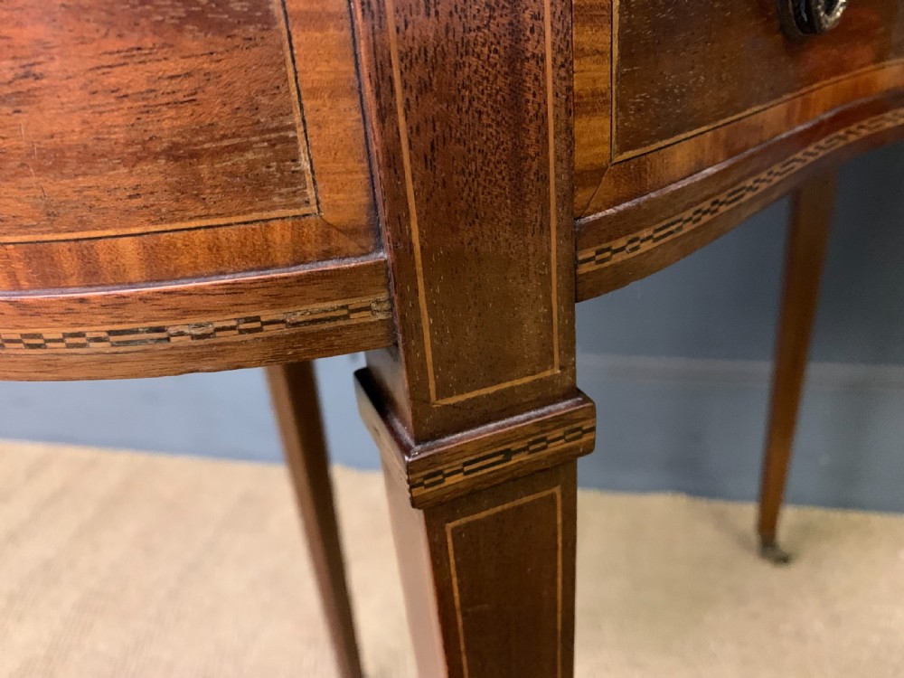 An Edwardian kidney-shaped mahogany table with central marquetry inlay, a single drawer with brass handles, and four tapered legs on castors. View XII