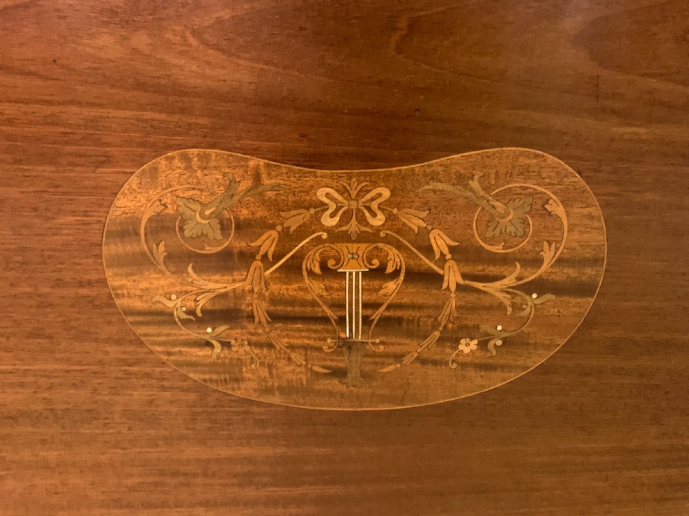 An Edwardian kidney-shaped mahogany table with central marquetry inlay, a single drawer with brass handles, and four tapered legs on castors. View XVI