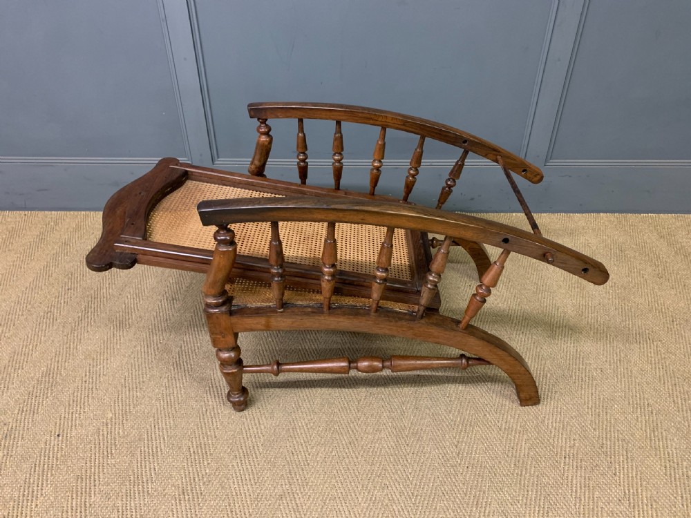 A 19th-century colonial reclining armchair crafted from dark wood with a hand-woven cane backrest and seat, featuring turned spindle arm supports. View XII