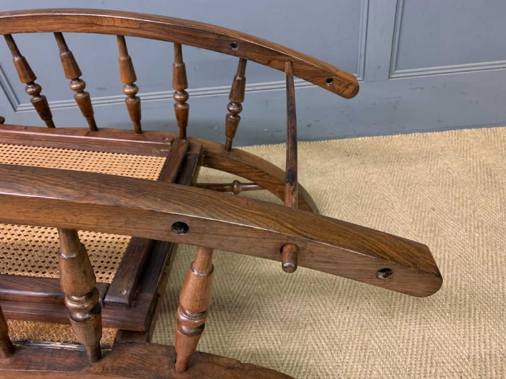 A 19th-century colonial reclining armchair crafted from dark wood with a hand-woven cane backrest and seat, featuring turned spindle arm supports. View XIII