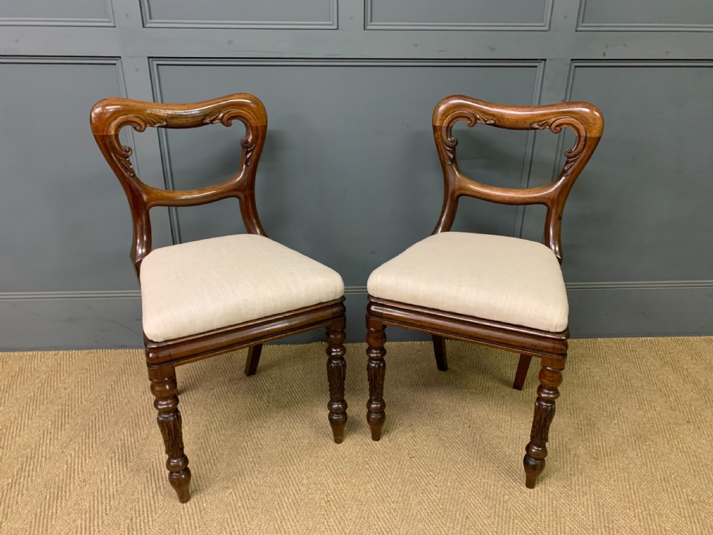 A set of eight early Victorian rosewood dining chairs featuring rounded balloon back frames, carved rail detailing, turned legs, and neutral upholstered seats. View IV