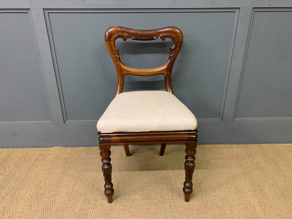 A set of eight early Victorian rosewood dining chairs featuring rounded balloon back frames, carved rail detailing, turned legs, and neutral upholstered seats. View VIII