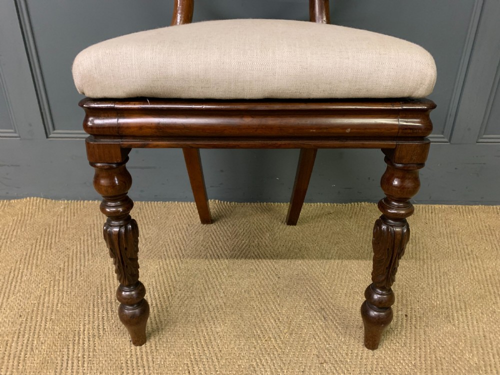 A set of eight early Victorian rosewood dining chairs featuring rounded balloon back frames, carved rail detailing, turned legs, and neutral upholstered seats. View XII