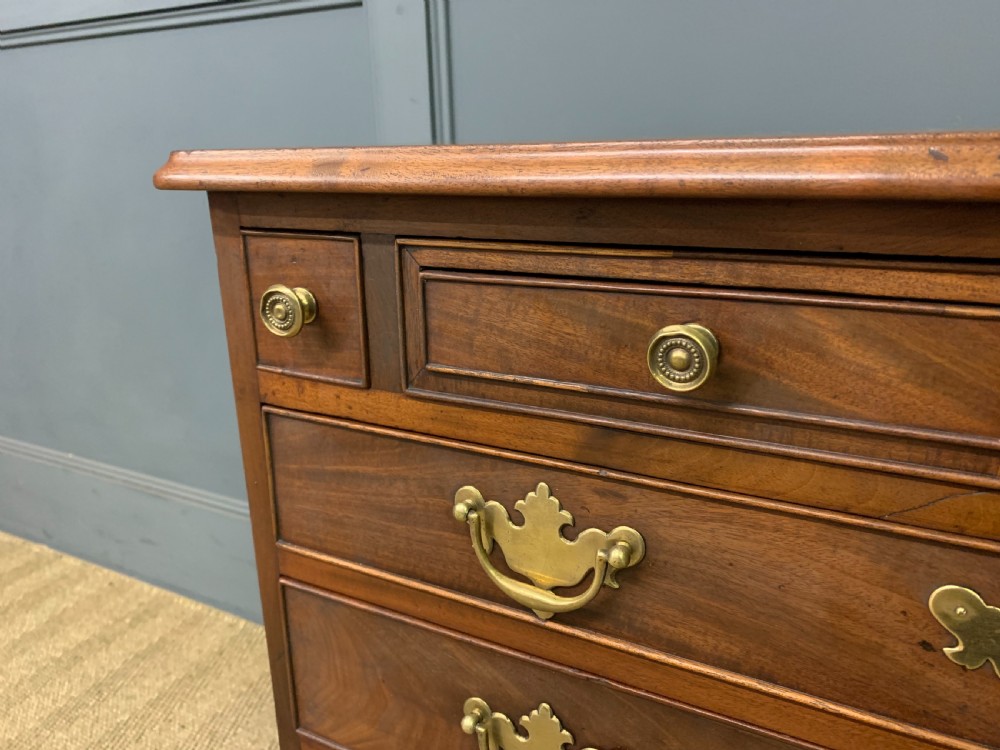 A Georgian mahogany bachelor chest featuring multiple drawers, brass handles, bracket feet, and an extended writing slide lined with green baize. View VII