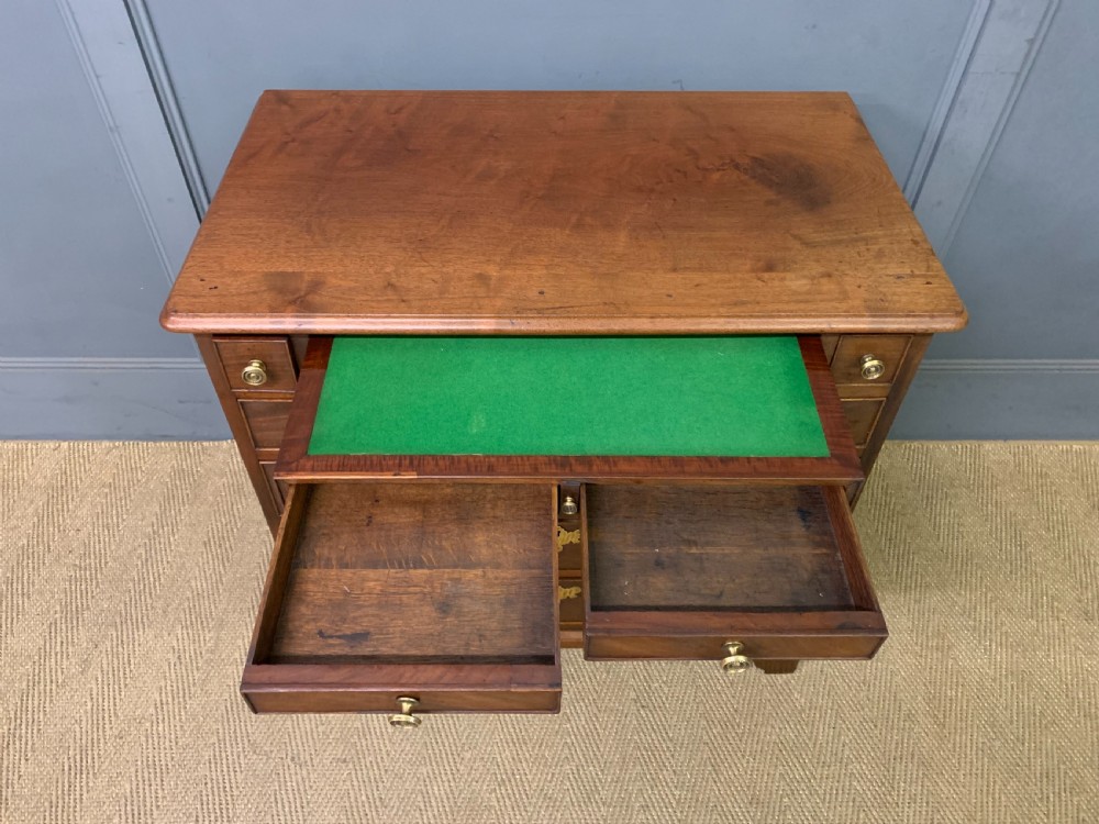 A Georgian mahogany bachelor chest featuring multiple drawers, brass handles, bracket feet, and an extended writing slide lined with green baize. View XIII