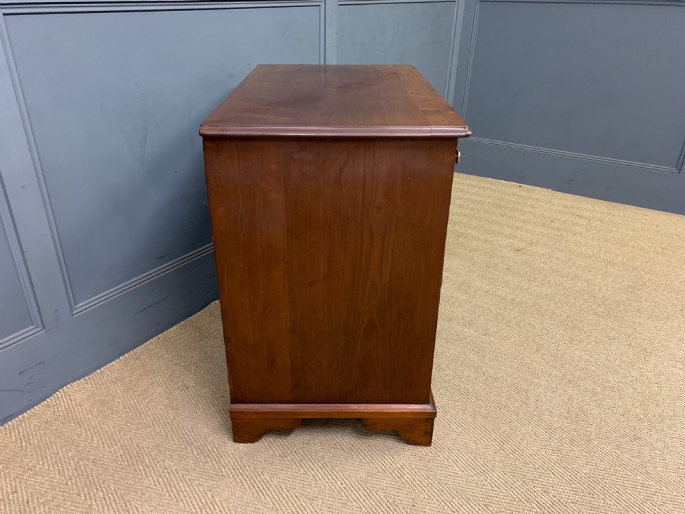 A Georgian mahogany bachelor chest featuring multiple drawers, brass handles, bracket feet, and an extended writing slide lined with green baize. View XVII