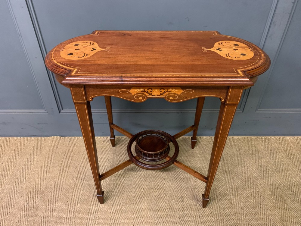 An Edwardian mahogany occasional table featuring intricate floral marquetry top inlays, tapered legs, and a central circular spindled undertier.