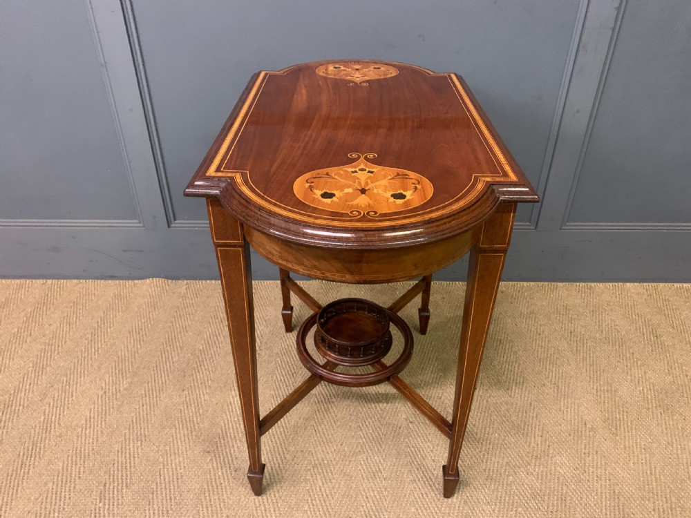An Edwardian mahogany occasional table featuring intricate floral marquetry top inlays, tapered legs, and a central circular spindled undertier. View X