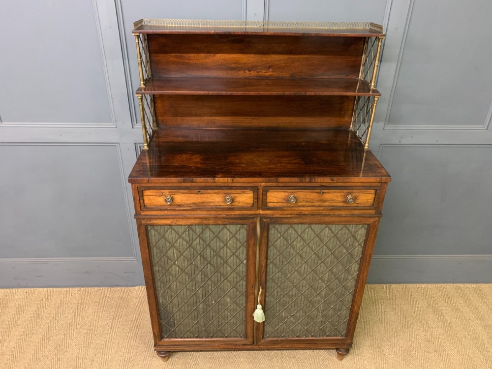 An antique Regency rosewood chiffonier featuring a brass lattice gallery shelf, two upper drawers, and lower doors with wire mesh and pleated fabric panels. View III