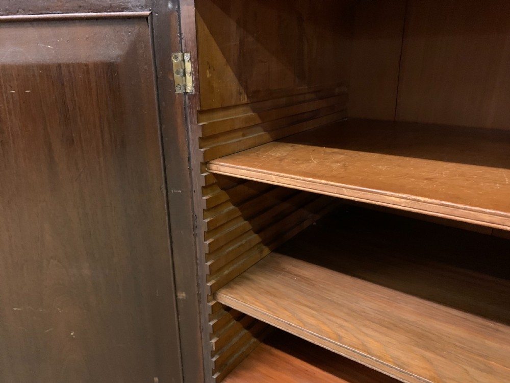 An antique Regency rosewood chiffonier featuring a brass lattice gallery shelf, two upper drawers, and lower doors with wire mesh and pleated fabric panels. View XIII