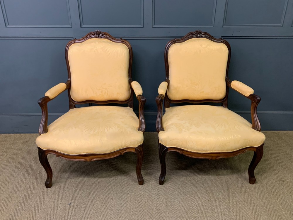 A pair of antique French rosewood fauteuil armchairs with carved serpentine frames, cabriole legs, and yellow floral damask upholstery. View II