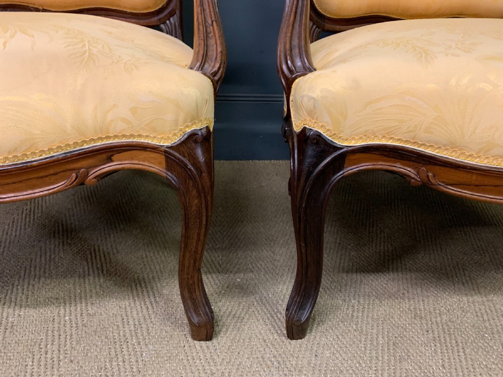 A pair of antique French rosewood fauteuil armchairs with carved serpentine frames, cabriole legs, and yellow floral damask upholstery. View III