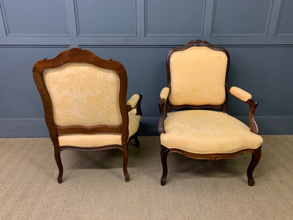A pair of antique French rosewood fauteuil armchairs with carved serpentine frames, cabriole legs, and yellow floral damask upholstery. View VI