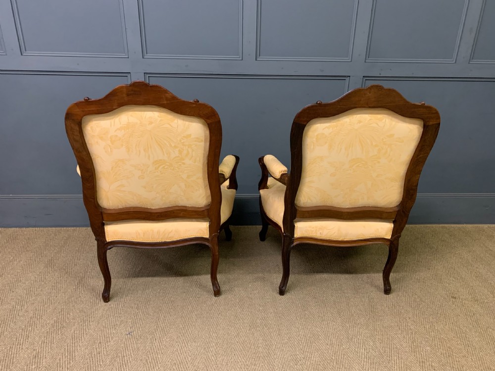 A pair of antique French rosewood fauteuil armchairs with carved serpentine frames, cabriole legs, and yellow floral damask upholstery. View VII