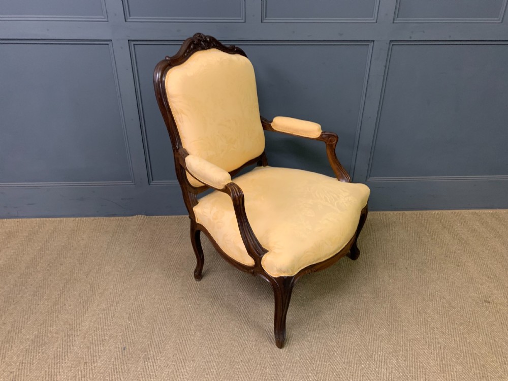 A pair of antique French rosewood fauteuil armchairs with carved serpentine frames, cabriole legs, and yellow floral damask upholstery. View XV