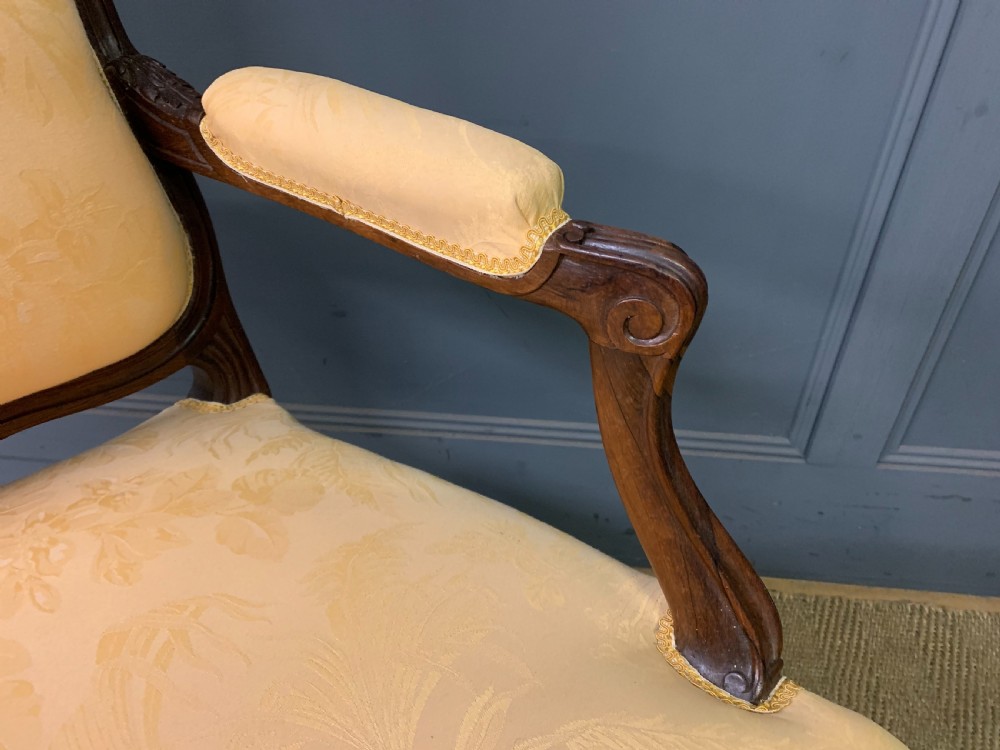 A pair of antique French rosewood fauteuil armchairs with carved serpentine frames, cabriole legs, and yellow floral damask upholstery. View XVI