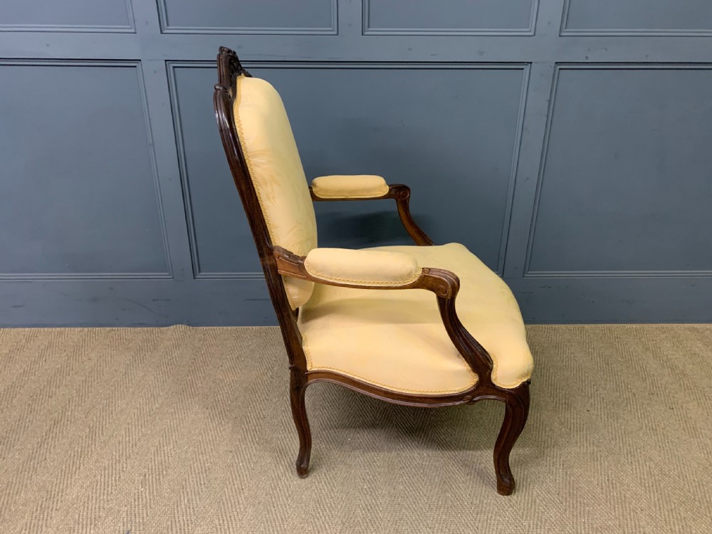 A pair of antique French rosewood fauteuil armchairs with carved serpentine frames, cabriole legs, and yellow floral damask upholstery. View XVIII