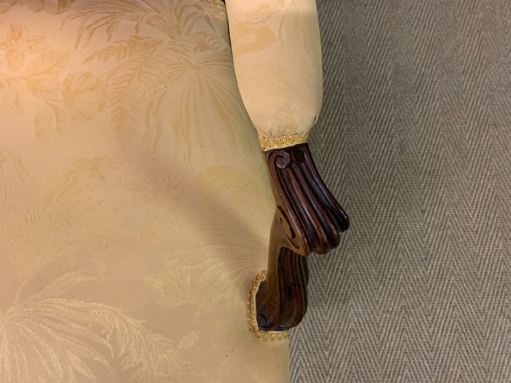 A pair of antique French rosewood fauteuil armchairs with carved serpentine frames, cabriole legs, and yellow floral damask upholstery. View XIX