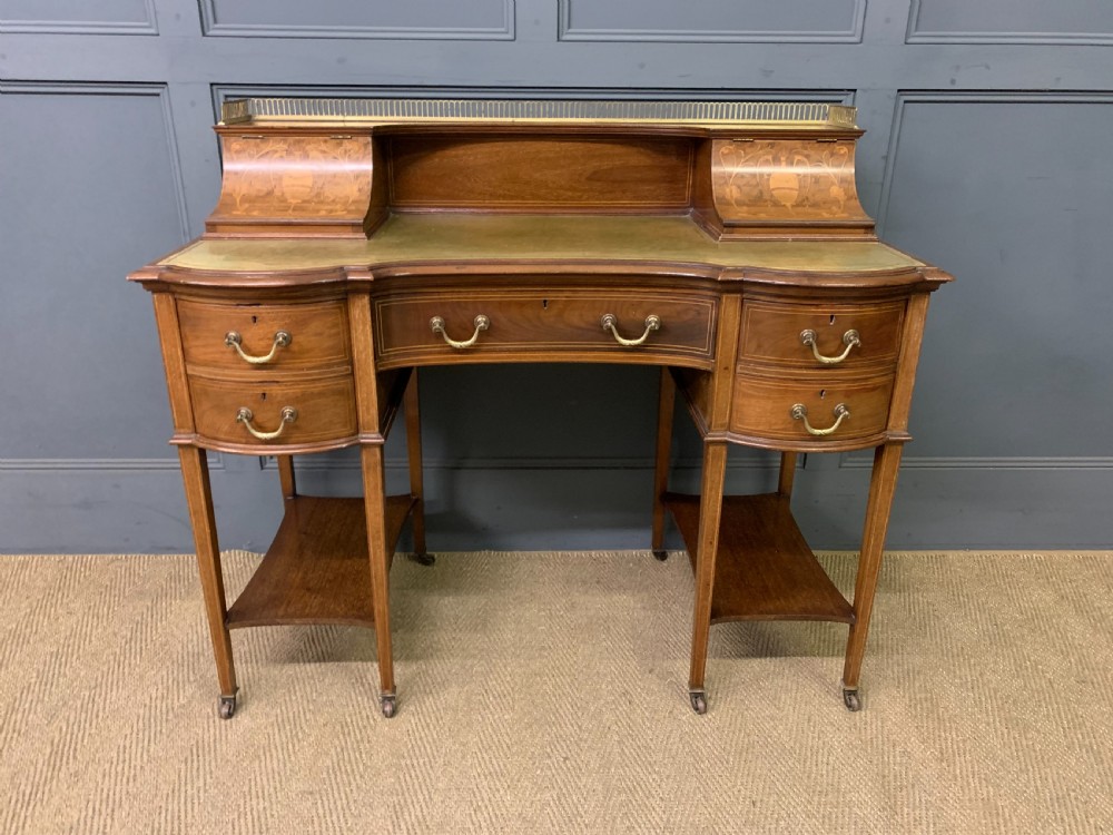 An Edwardian mahogany writing desk featuring a green leather surface, brass gallery rail, marquetry sloped panels, and drawer pedestals on tapered legs. View III