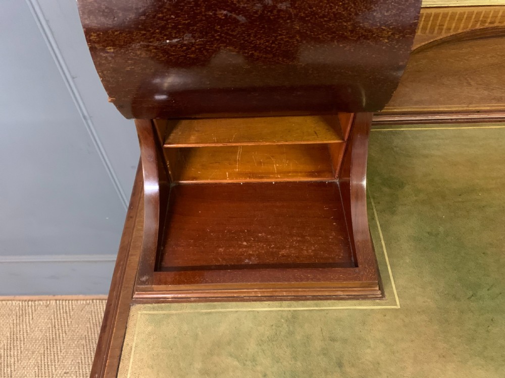 An Edwardian mahogany writing desk featuring a green leather surface, brass gallery rail, marquetry sloped panels, and drawer pedestals on tapered legs. View XIV