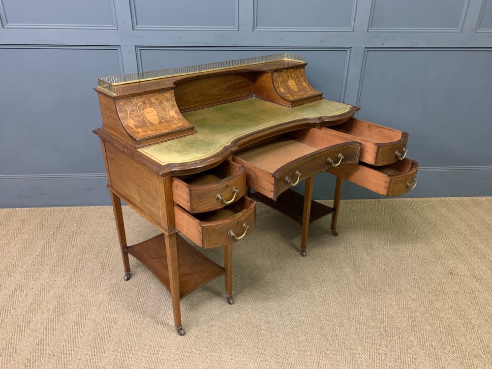 An Edwardian mahogany writing desk featuring a green leather surface, brass gallery rail, marquetry sloped panels, and drawer pedestals on tapered legs. View XVIII