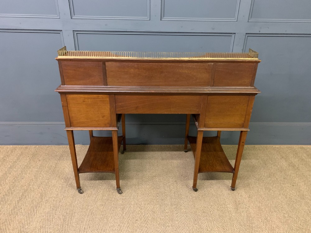 An Edwardian mahogany writing desk featuring a green leather surface, brass gallery rail, marquetry sloped panels, and drawer pedestals on tapered legs. View XXII