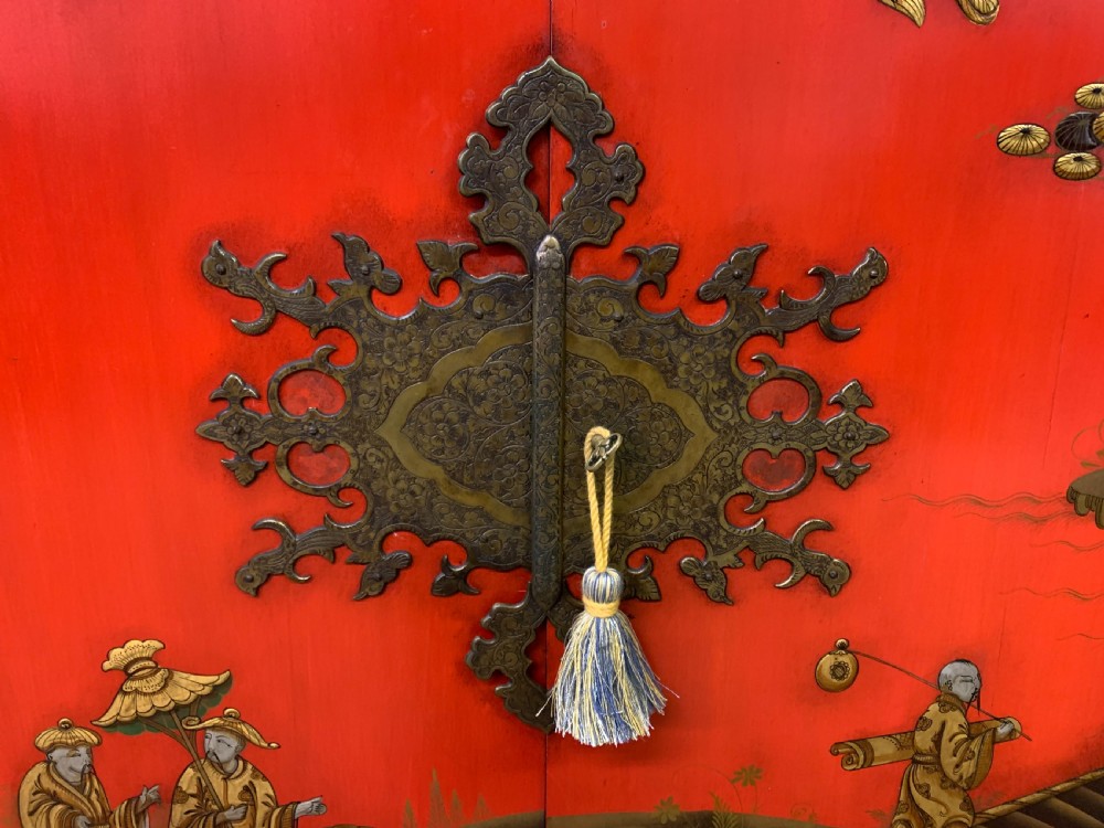 A bright red lacquered Chinoiserie cabinet with gold hand-painted figures and landscapes, mounted on an ornate carved giltwood stand with cabriole legs. View V
