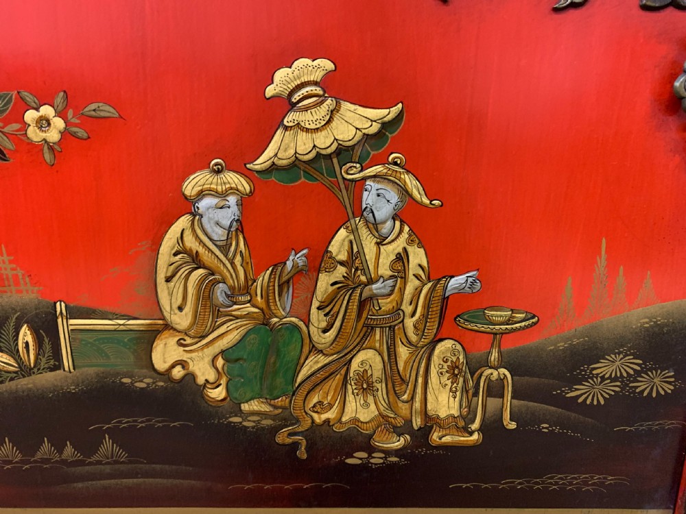 A bright red lacquered Chinoiserie cabinet with gold hand-painted figures and landscapes, mounted on an ornate carved giltwood stand with cabriole legs. View VI
