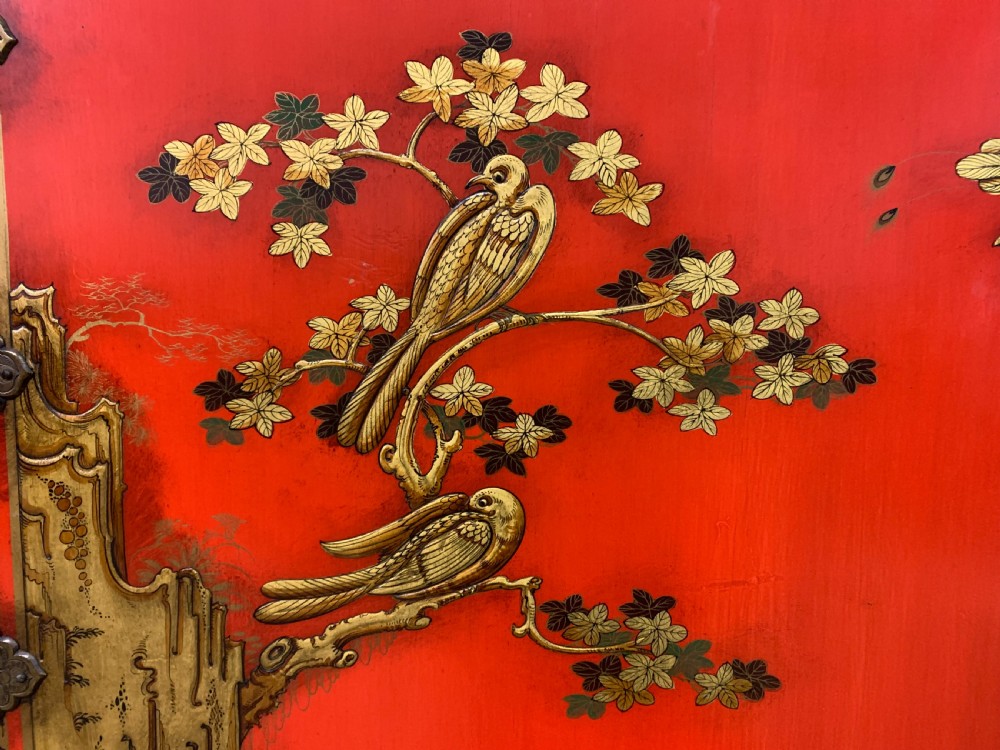 A bright red lacquered Chinoiserie cabinet with gold hand-painted figures and landscapes, mounted on an ornate carved giltwood stand with cabriole legs. View VII
