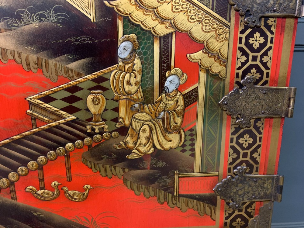 A bright red lacquered Chinoiserie cabinet with gold hand-painted figures and landscapes, mounted on an ornate carved giltwood stand with cabriole legs. View IX