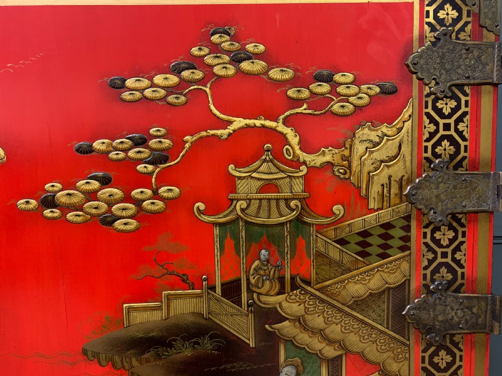 A bright red lacquered Chinoiserie cabinet with gold hand-painted figures and landscapes, mounted on an ornate carved giltwood stand with cabriole legs. View X