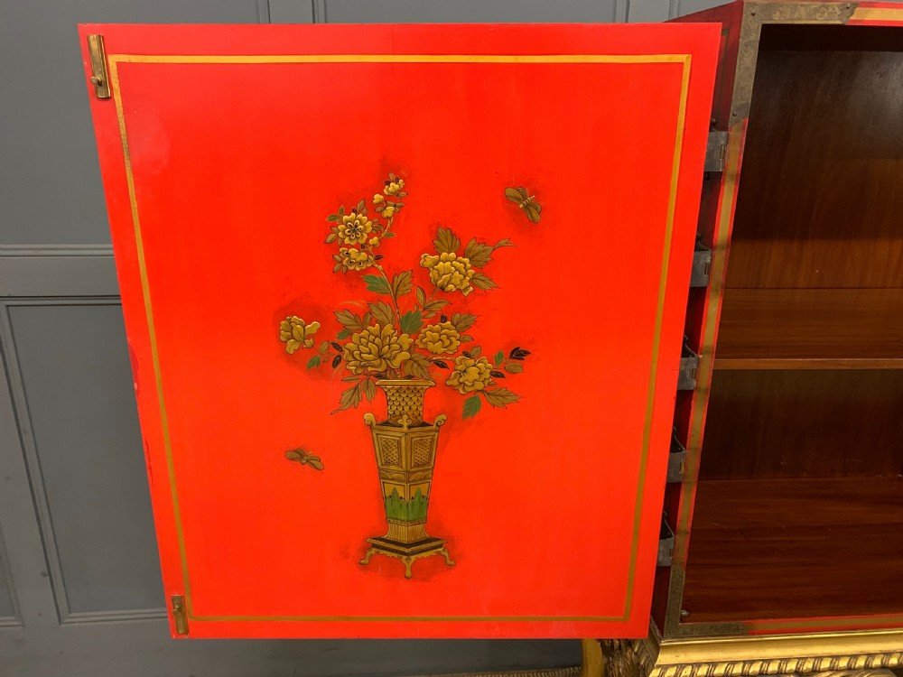 A bright red lacquered Chinoiserie cabinet with gold hand-painted figures and landscapes, mounted on an ornate carved giltwood stand with cabriole legs. View XV