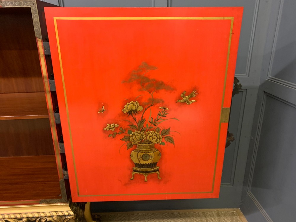 A bright red lacquered Chinoiserie cabinet with gold hand-painted figures and landscapes, mounted on an ornate carved giltwood stand with cabriole legs. View XVI