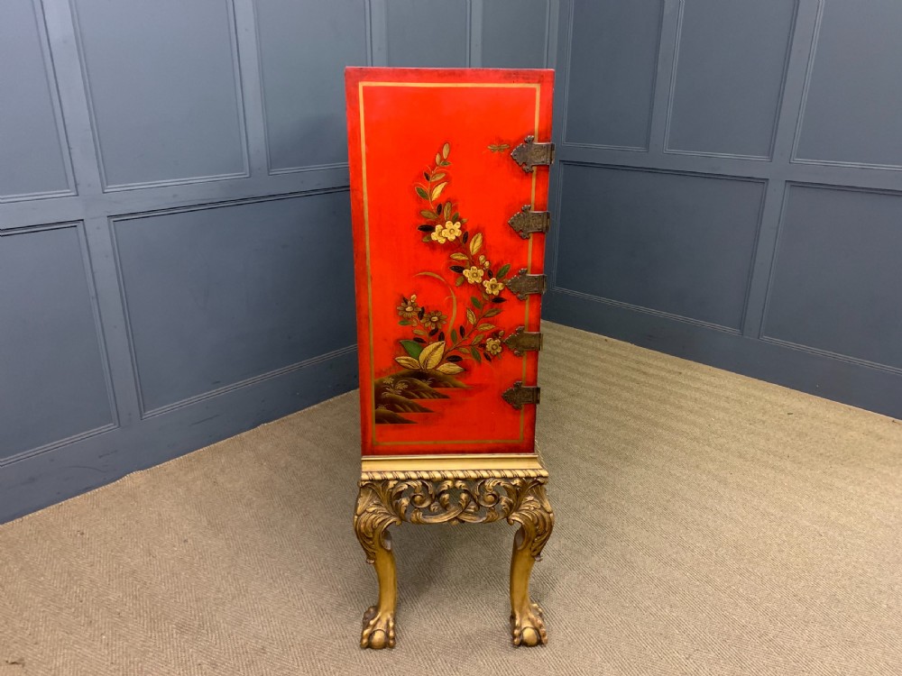 A bright red lacquered Chinoiserie cabinet with gold hand-painted figures and landscapes, mounted on an ornate carved giltwood stand with cabriole legs. View XVIII