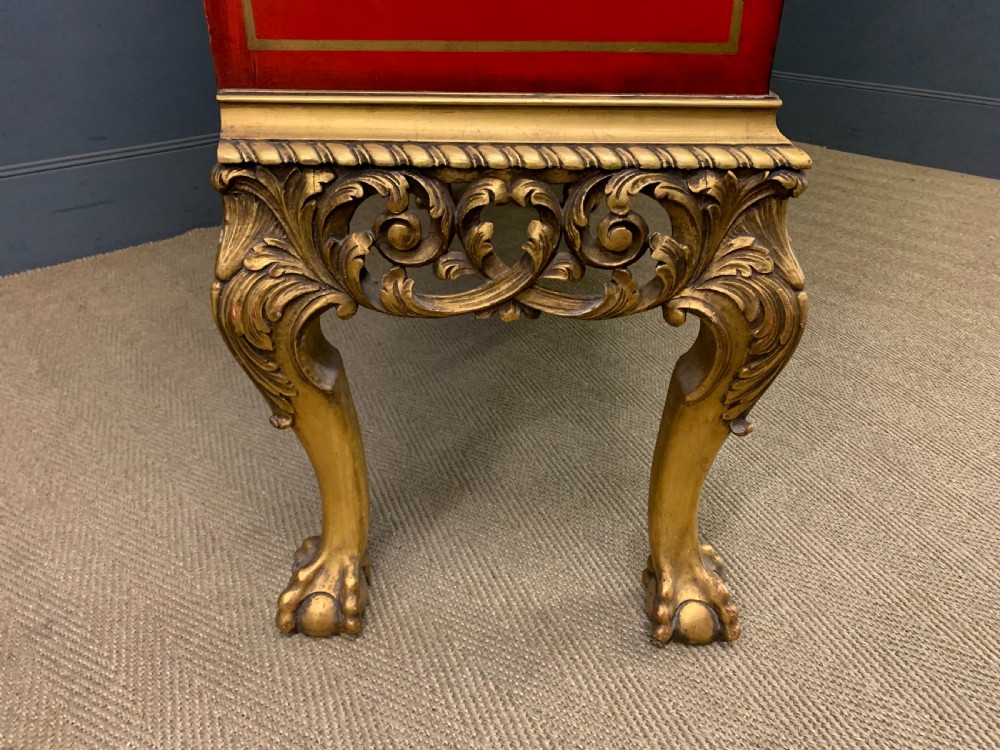 A bright red lacquered Chinoiserie cabinet with gold hand-painted figures and landscapes, mounted on an ornate carved giltwood stand with cabriole legs. View XIX