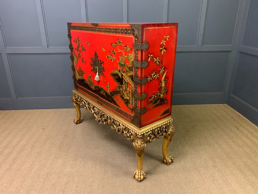 A bright red lacquered Chinoiserie cabinet with gold hand-painted figures and landscapes, mounted on an ornate carved giltwood stand with cabriole legs. View XXIII