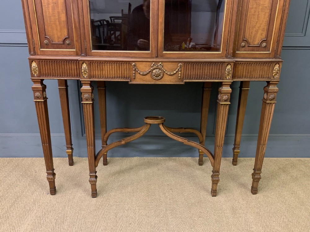 An antique mahogany display cabinet featuring glazed centre doors, side inlaid panels, fluted legs, and an arched top. View III