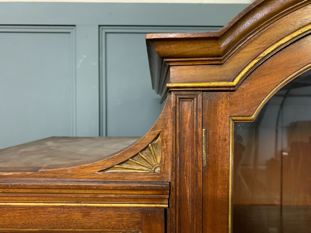 An antique mahogany display cabinet featuring glazed centre doors, side inlaid panels, fluted legs, and an arched top. View XIII