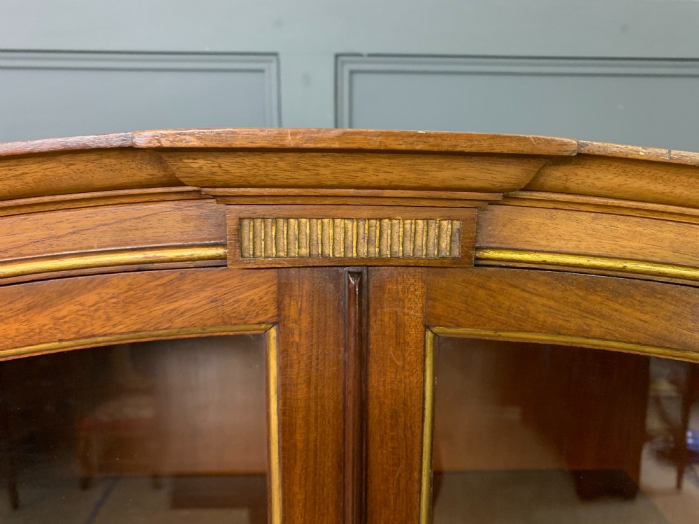 An antique mahogany display cabinet featuring glazed centre doors, side inlaid panels, fluted legs, and an arched top. View XIV