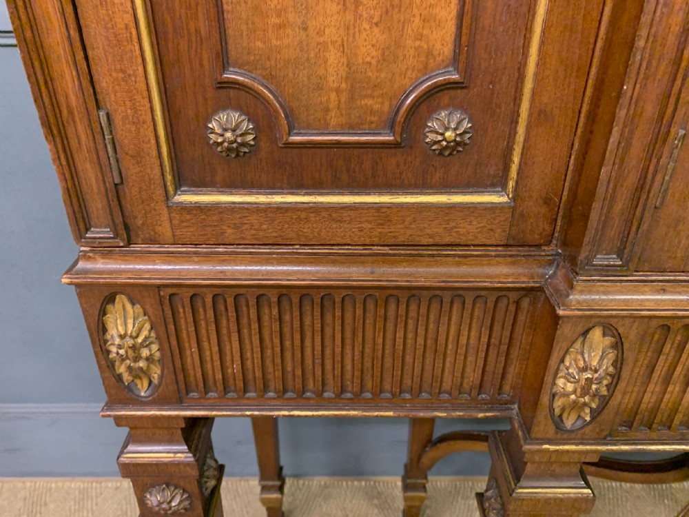An antique mahogany display cabinet featuring glazed centre doors, side inlaid panels, fluted legs, and an arched top. View XV