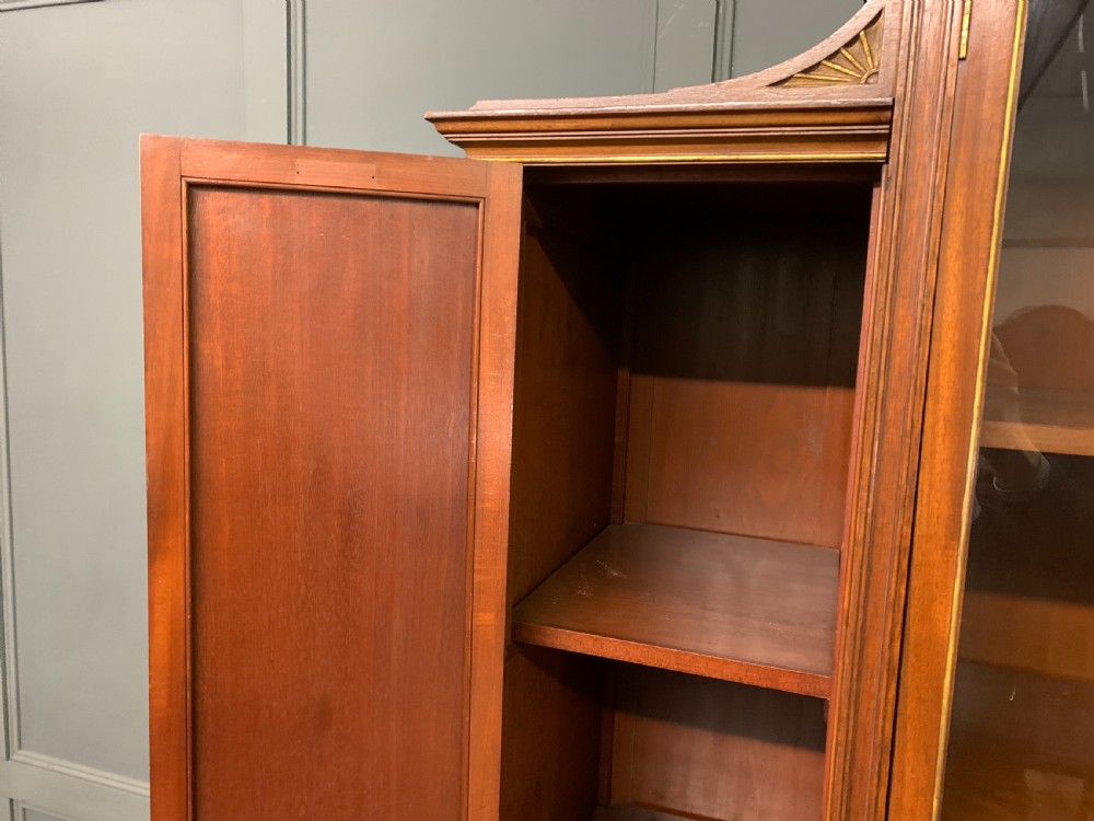 An antique mahogany display cabinet featuring glazed centre doors, side inlaid panels, fluted legs, and an arched top. View XVII