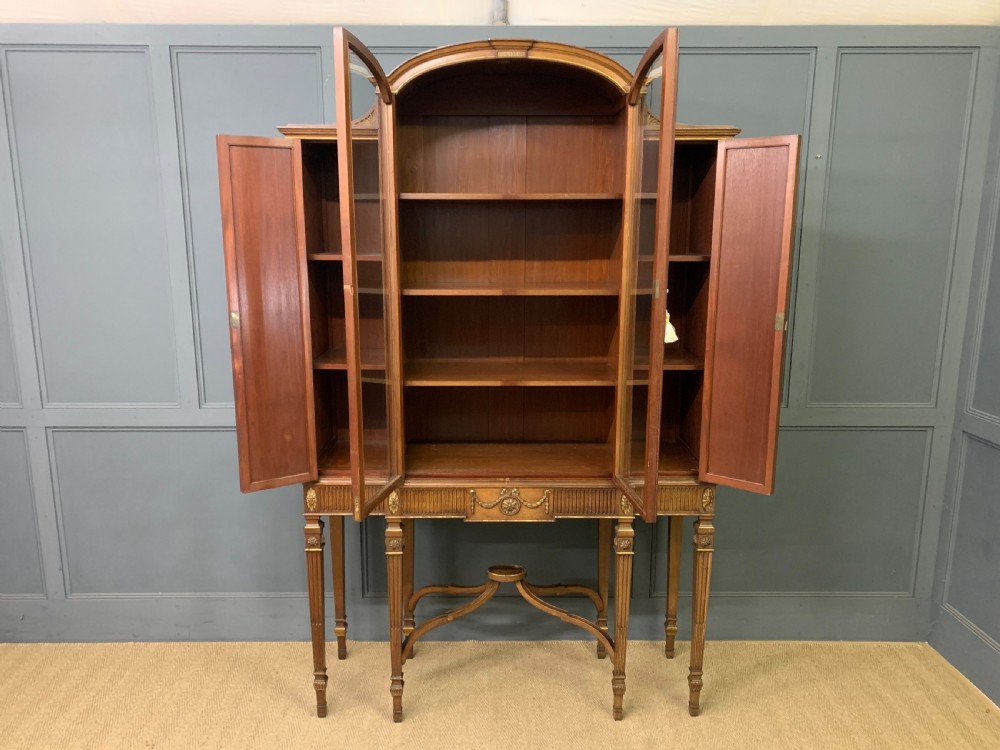An antique mahogany display cabinet featuring glazed centre doors, side inlaid panels, fluted legs, and an arched top. View XVIII