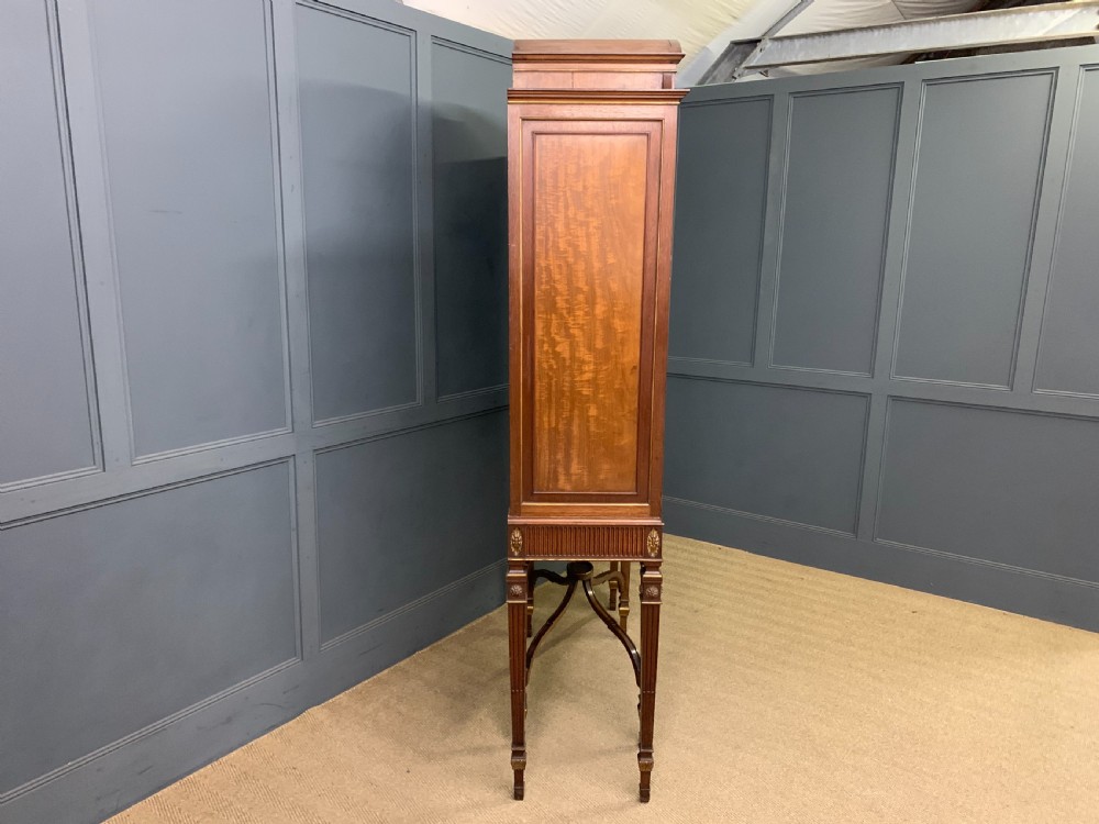 An antique mahogany display cabinet featuring glazed centre doors, side inlaid panels, fluted legs, and an arched top. View XXIII