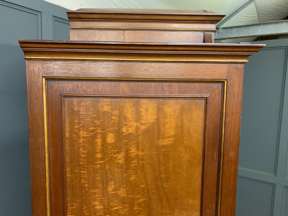 An antique mahogany display cabinet featuring glazed centre doors, side inlaid panels, fluted legs, and an arched top. View XXV