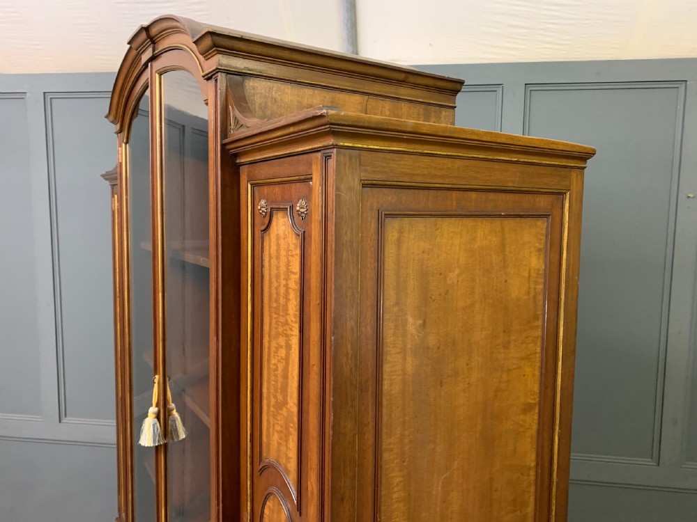 An antique mahogany display cabinet featuring glazed centre doors, side inlaid panels, fluted legs, and an arched top. View XXVIII