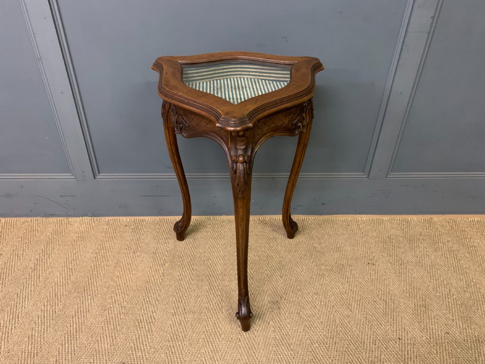 A French carved walnut bijouterie table featuring a trefoil-shaped hinged glass top, cabriole legs, and a striped fabric interior lining. View II