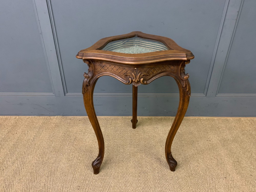 A French carved walnut bijouterie table featuring a trefoil-shaped hinged glass top, cabriole legs, and a striped fabric interior lining. View VI