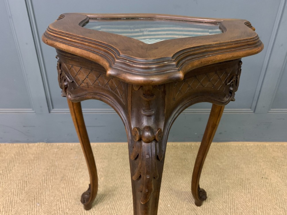 A French carved walnut bijouterie table featuring a trefoil-shaped hinged glass top, cabriole legs, and a striped fabric interior lining. View X