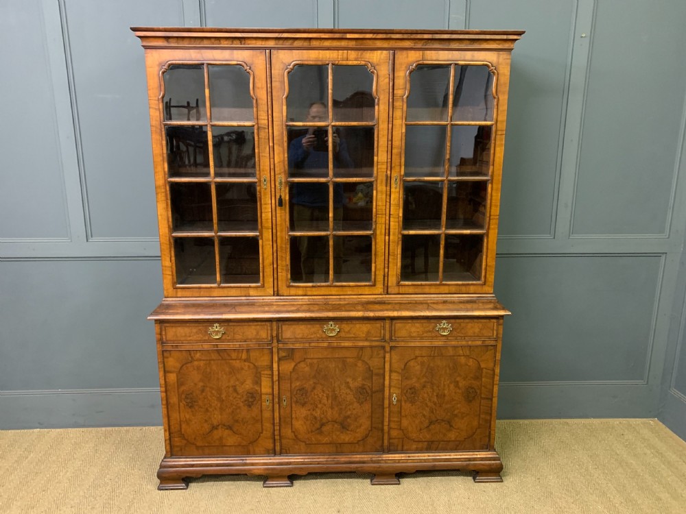 A large three-door burr walnut bookcase with glazed upper doors, three frieze drawers, and crossbanded cupboard doors below. View II